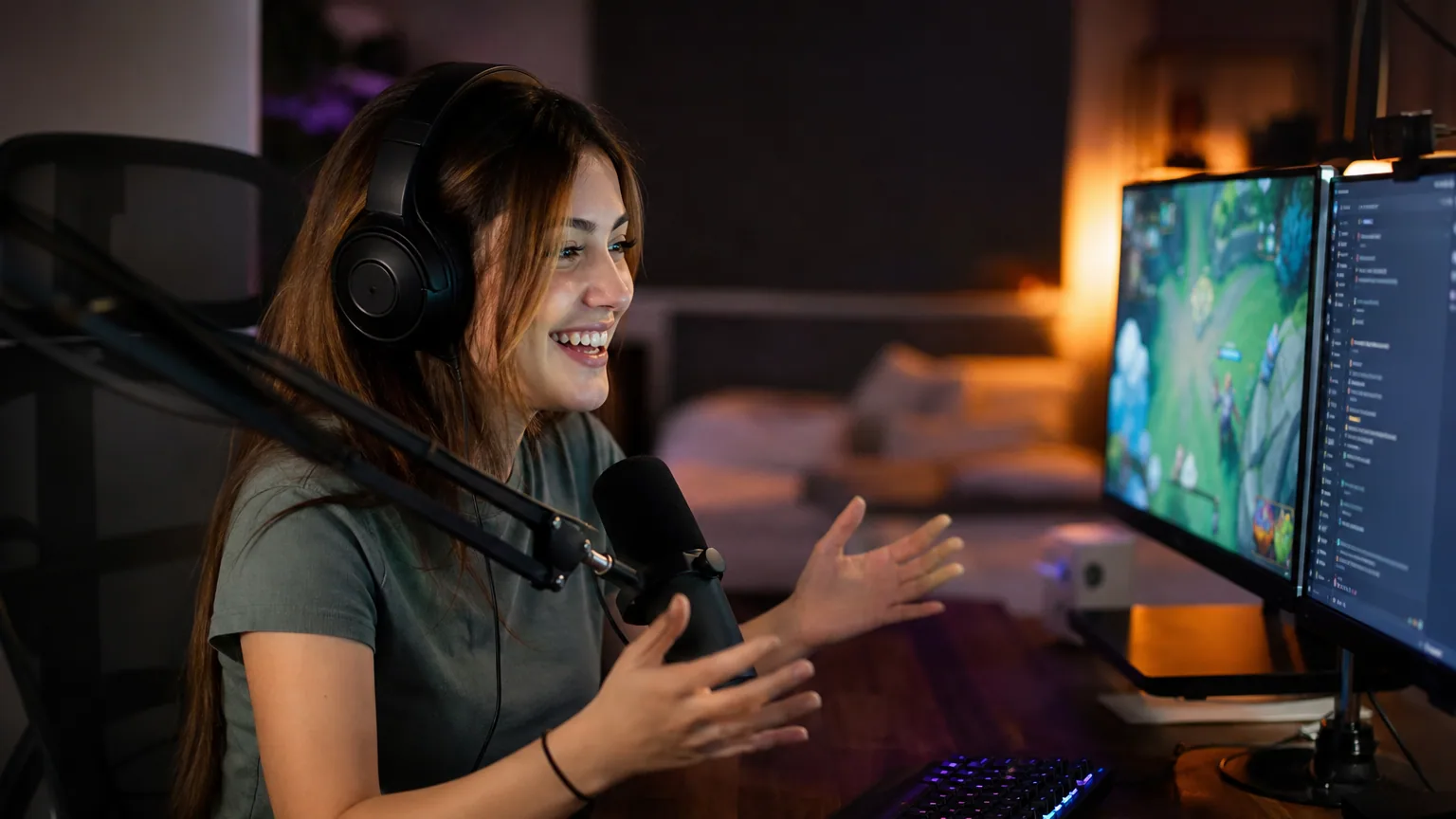 Un jeune streamer souriant face à sa webcam et son micro, avec deux écrans affichant un jeu et un chat.