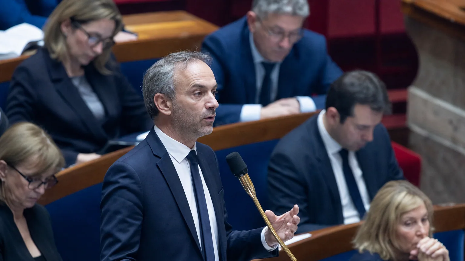 Un député s'exprime à la tribune dans l'hémicycle de l'Assemblée nationale pendant un débat.