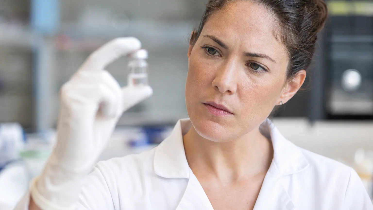 Une chercheuse en blouse blanche examine un flacon de vaccin dans un laboratoire