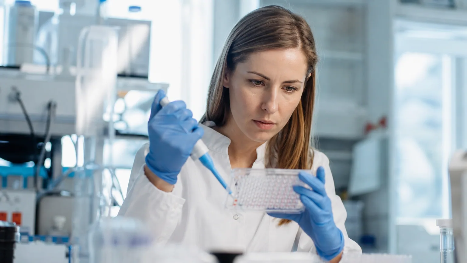Une chercheuse en blouse blanche manipule des échantillons dans un laboratoire de génétique