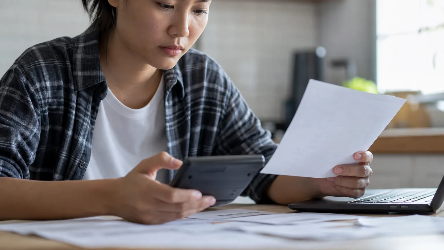 Une personne examine sa fiche de paie avec une calculatrice à la main