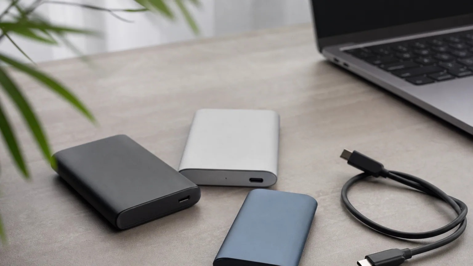 Plusieurs SSD externes compacts posés sur un bureau à côté d'un ordinateur portable