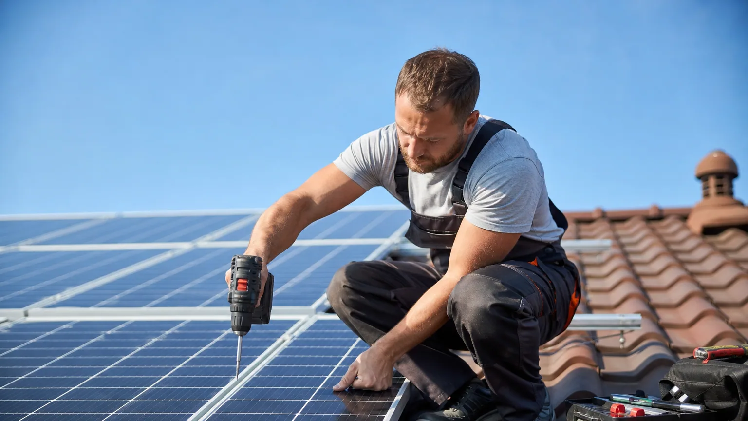 Un installateur fixe des panneaux solaires photovoltaïques sur le toit d'une maison par temps clair