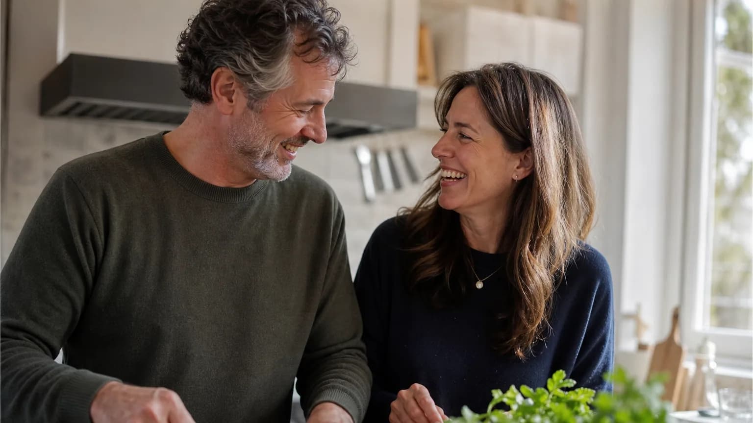 Un couple complice rit en cuisinant ensemble dans une cuisine chaleureuse